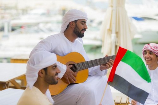 Arab man playing an instrument while celebrating the UAE National Day|