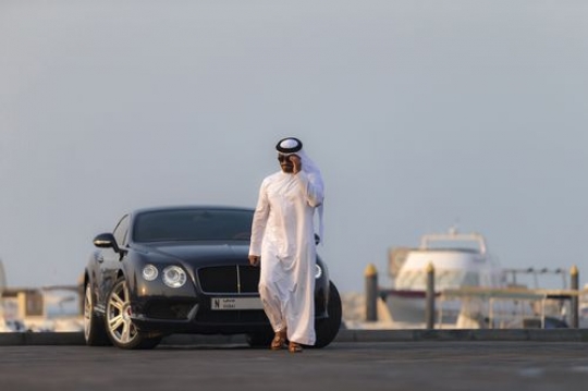 Arab man dressed in the traditional attire moving away from vehicle|-