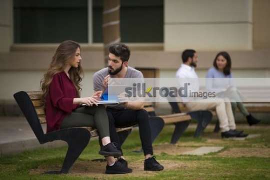 Middle Eastern man talking to the woman on the bench|