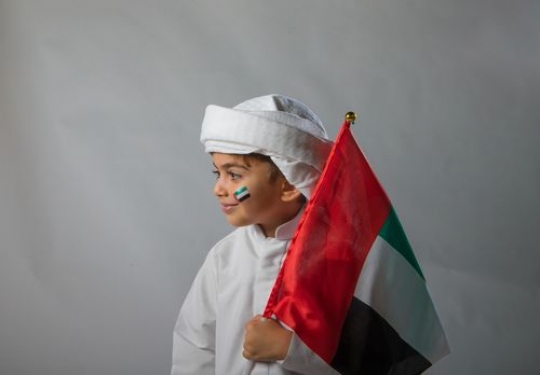 Emirati kid carrying a UAE Flag