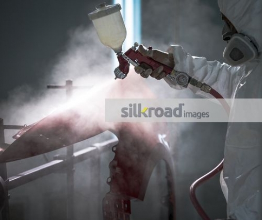 Mechanic painting the part of the car red|