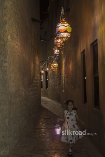 Arab girl carrying a Ramadan Lantern and running through the alleyway |-