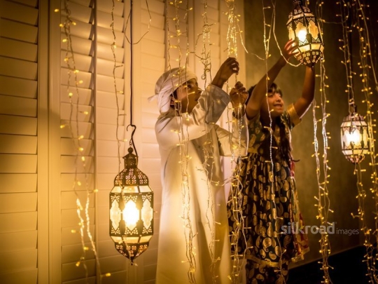 Brother and sister fixing ramadan lanterns|-