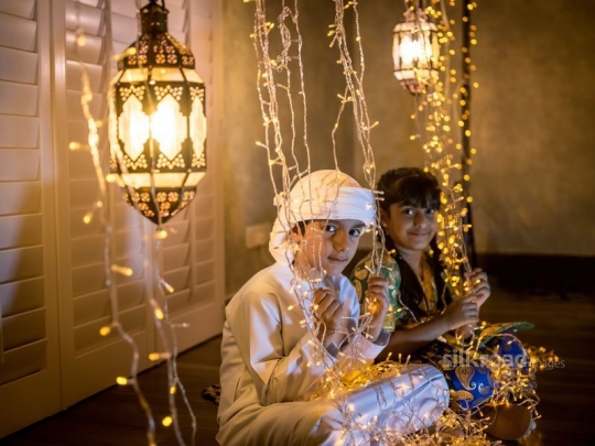 Boy and girl sitting on the floor in Ramadan|-