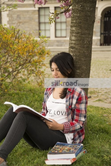 Woman leaning on the tree reading the book|