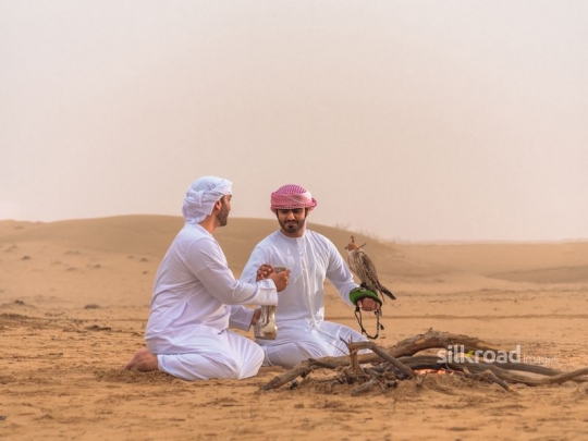 Friends drinking arabic coffee in the desert