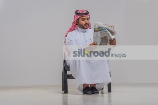 Businessman sitting on the chair reading the newspaper