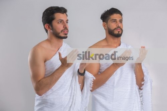 Medium shot of  Middle Eastern men dressed in the religious attire praying|