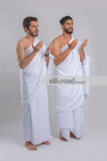 Middle Eastern men dressed in the religious attire praying|