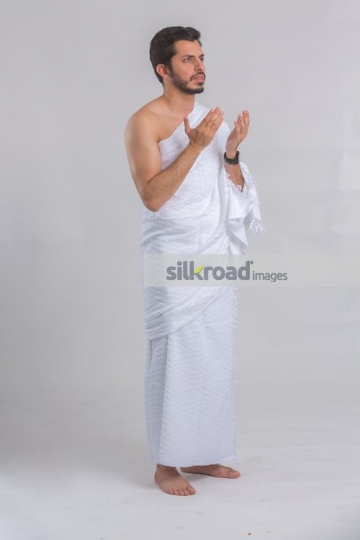 Middle Eastern man dressed in the religious attire praying|