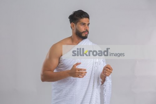 Medium shot of a Middle Eastern man dressed in the religious attire|