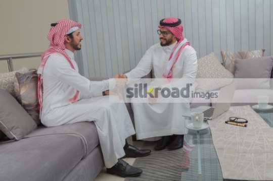 Businessmen sitting on the couch shaking hands|