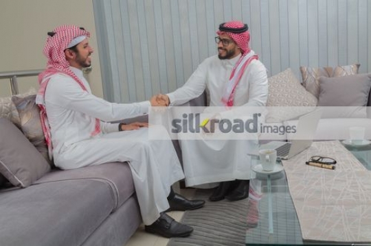 Middle Eastern Businessmen sitting on the couch shaking hands|